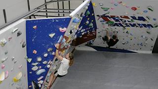 图为学生攀爬NMT抱石墙. 墙壁由蓝白相间的面板组成.
